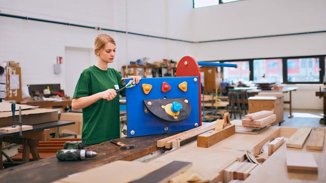 Ausbildung Tischler:in Eine Auszubildende repariert ein Spielgerät.