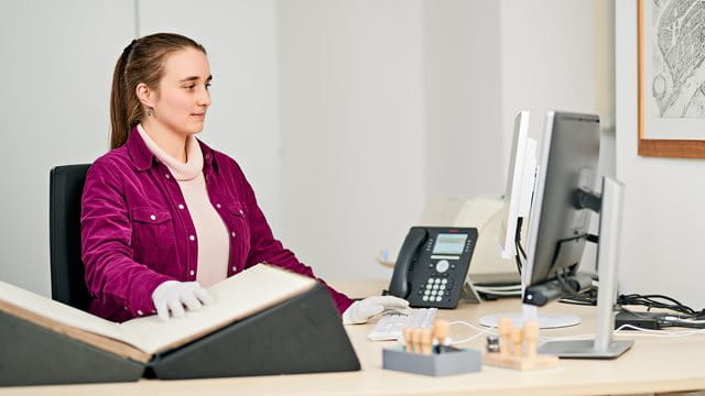 Duales Studium Anwärter:in für den gehobenen Archivdienst (Diplom-Archivar:in) Eine Studentin recherchiert in historischen Unterlagen und am Computer.